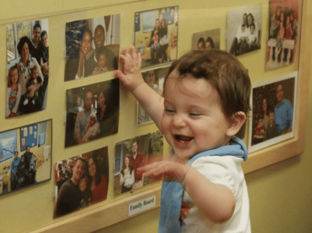 young child looking at photos on wall