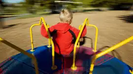 Preschool child playing on a merry go round