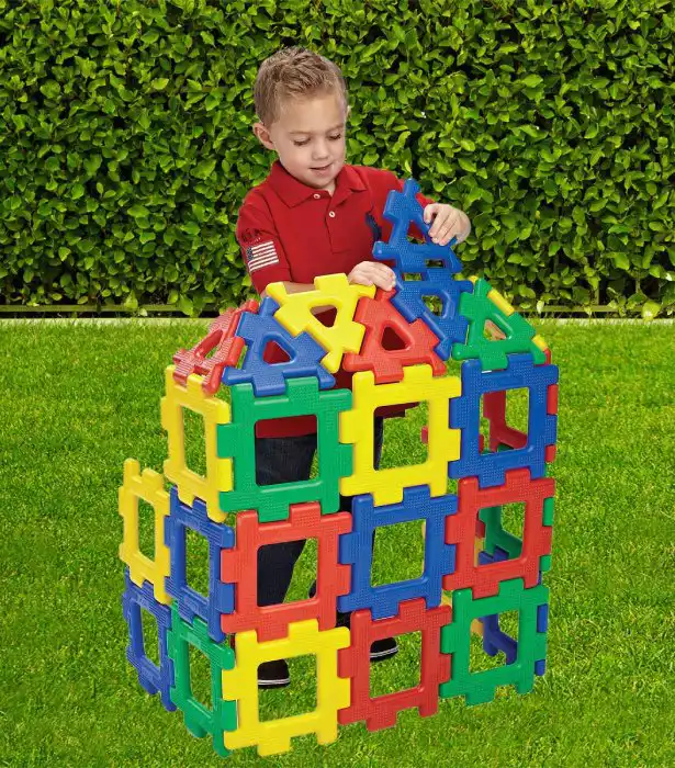 Young child learning outdoors with large colorful polydron