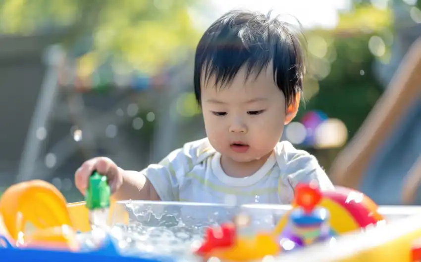 Toddler enjoying outdoor early learning activity in sensory water table