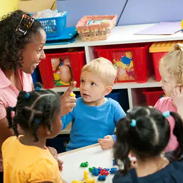Preschool teacher at table with children