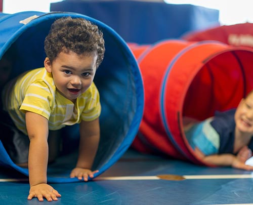 Preschool children climbing out of tunnel