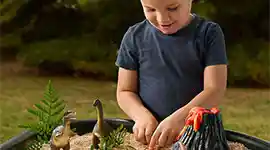 A child enjoying sensory play outside with in a Tuff Tray from Becker’s School Supplies. 