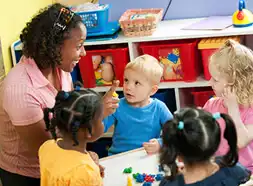 Preschool teacher at table with children