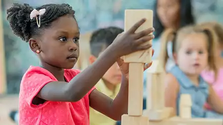 Preschool girl building with wood blocks