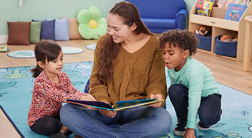 Preschool teacher reading to two children