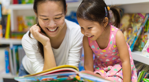 Preschool teacher reading a book to a child