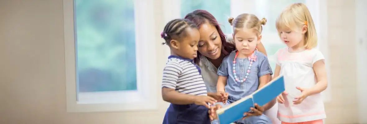 preschool teacher sitting reading to children